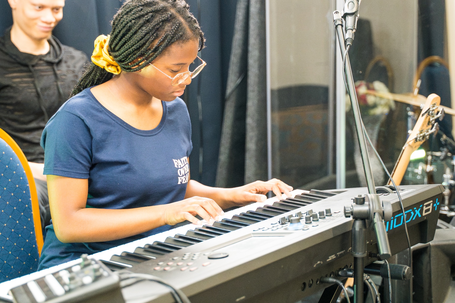 Young keyboardist in Faith Over Fear shirt playing during worship