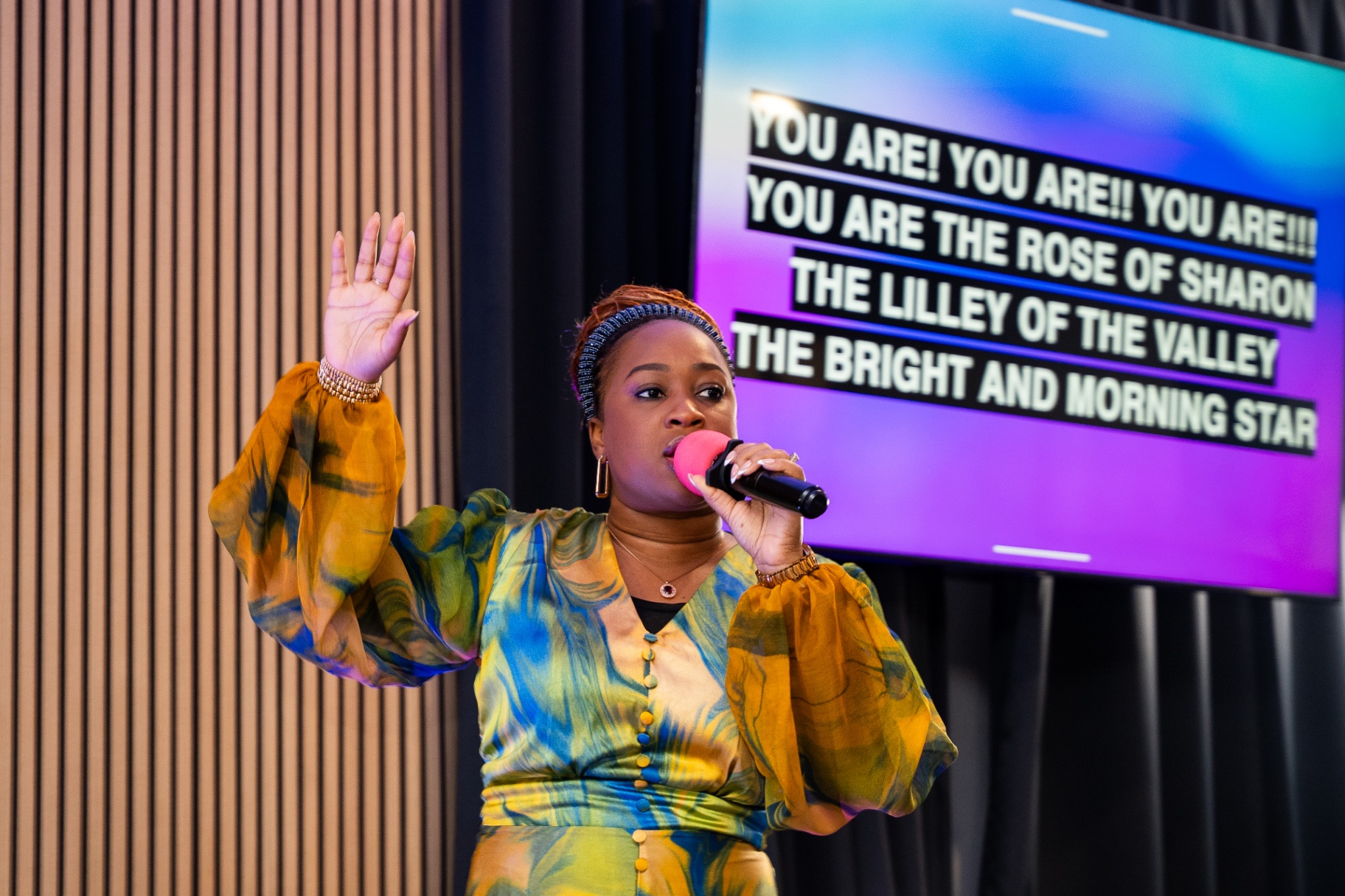Worship leader singing with lyrics displayed behind her