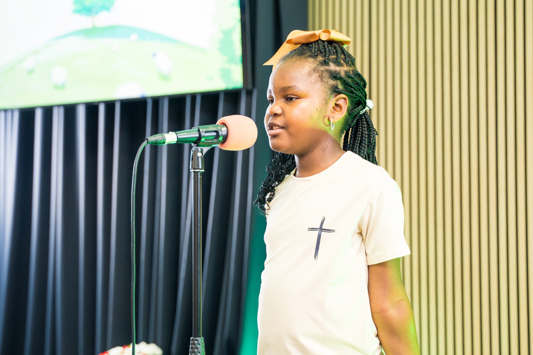 Young girl singing into a microphone during Kids and Youth service