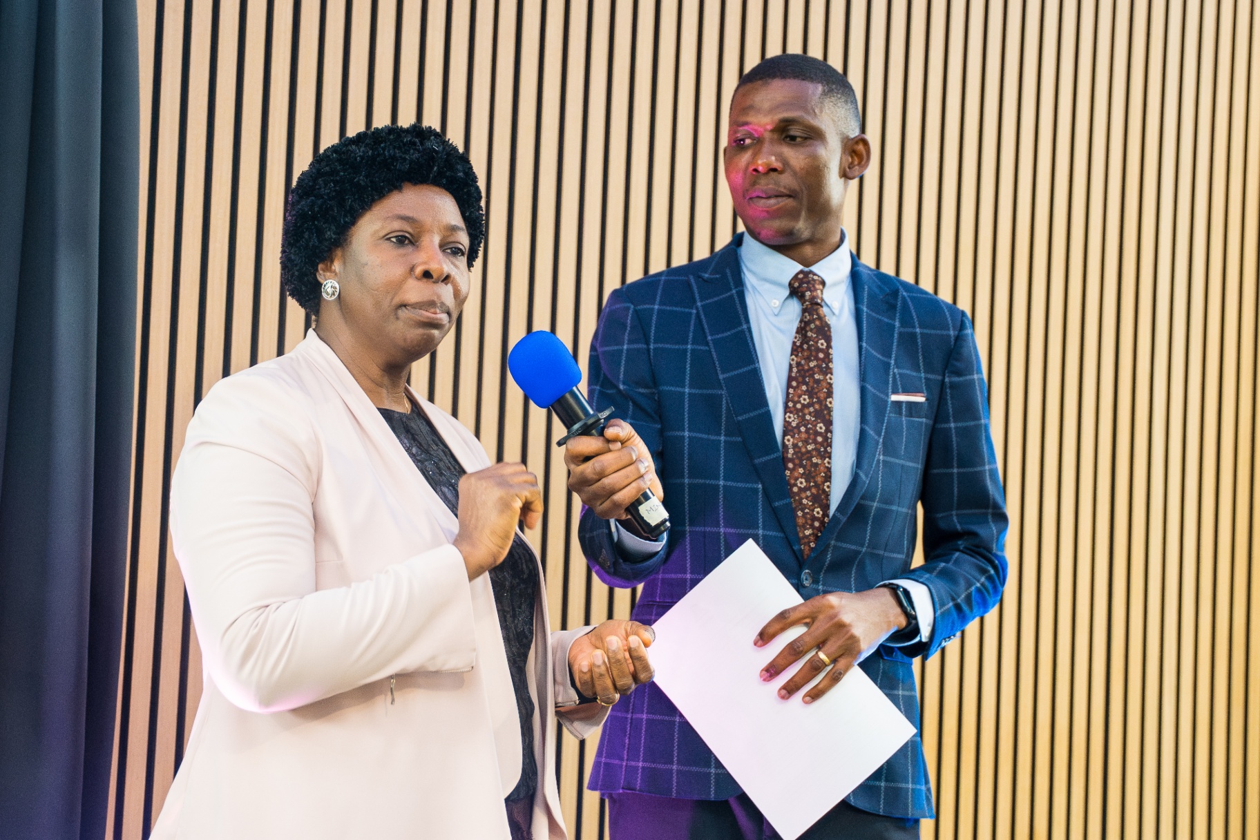 Woman sharing a testimony while being interviewed on stage
