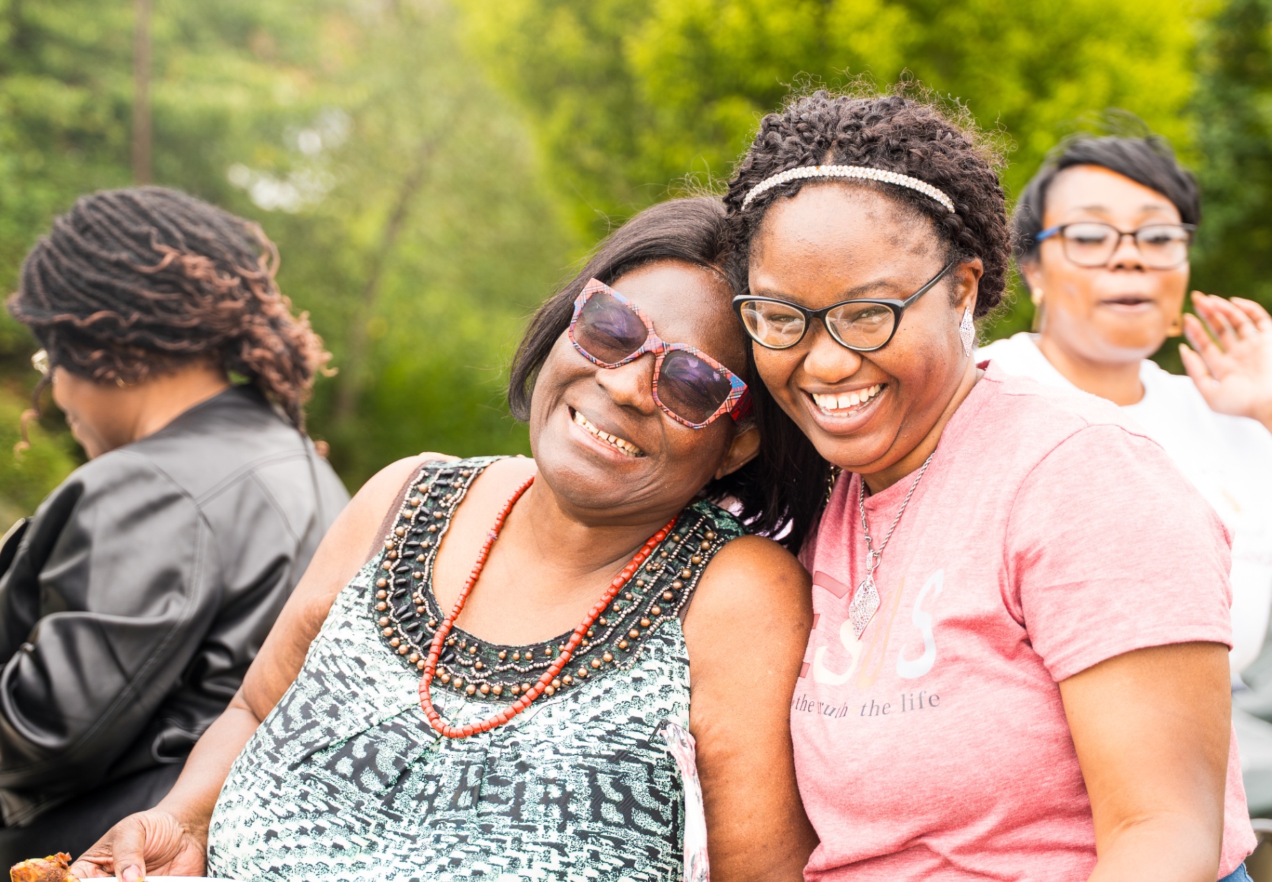 Two church members smiling and embracing during outdoor fellowship