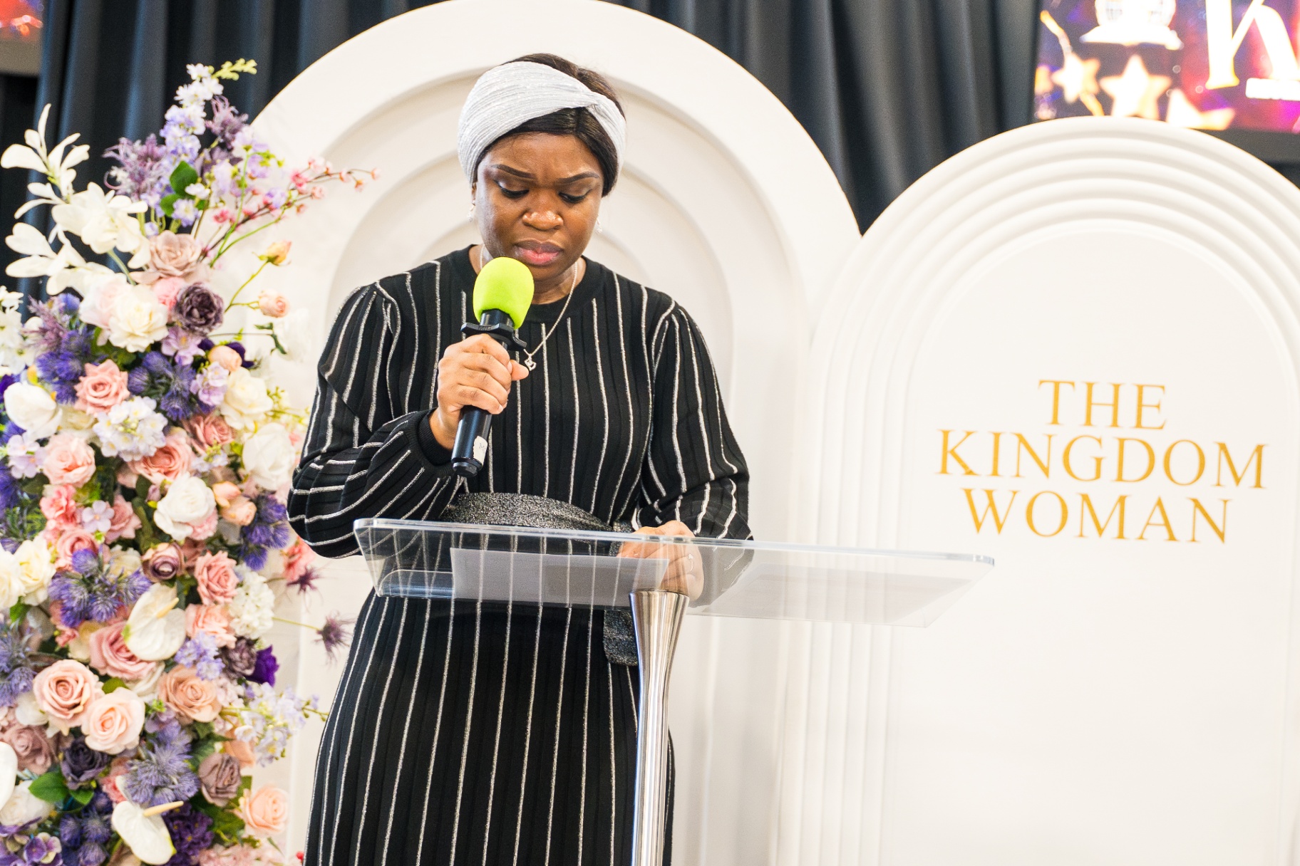 Woman praying at The Kingdom Woman conference lectern