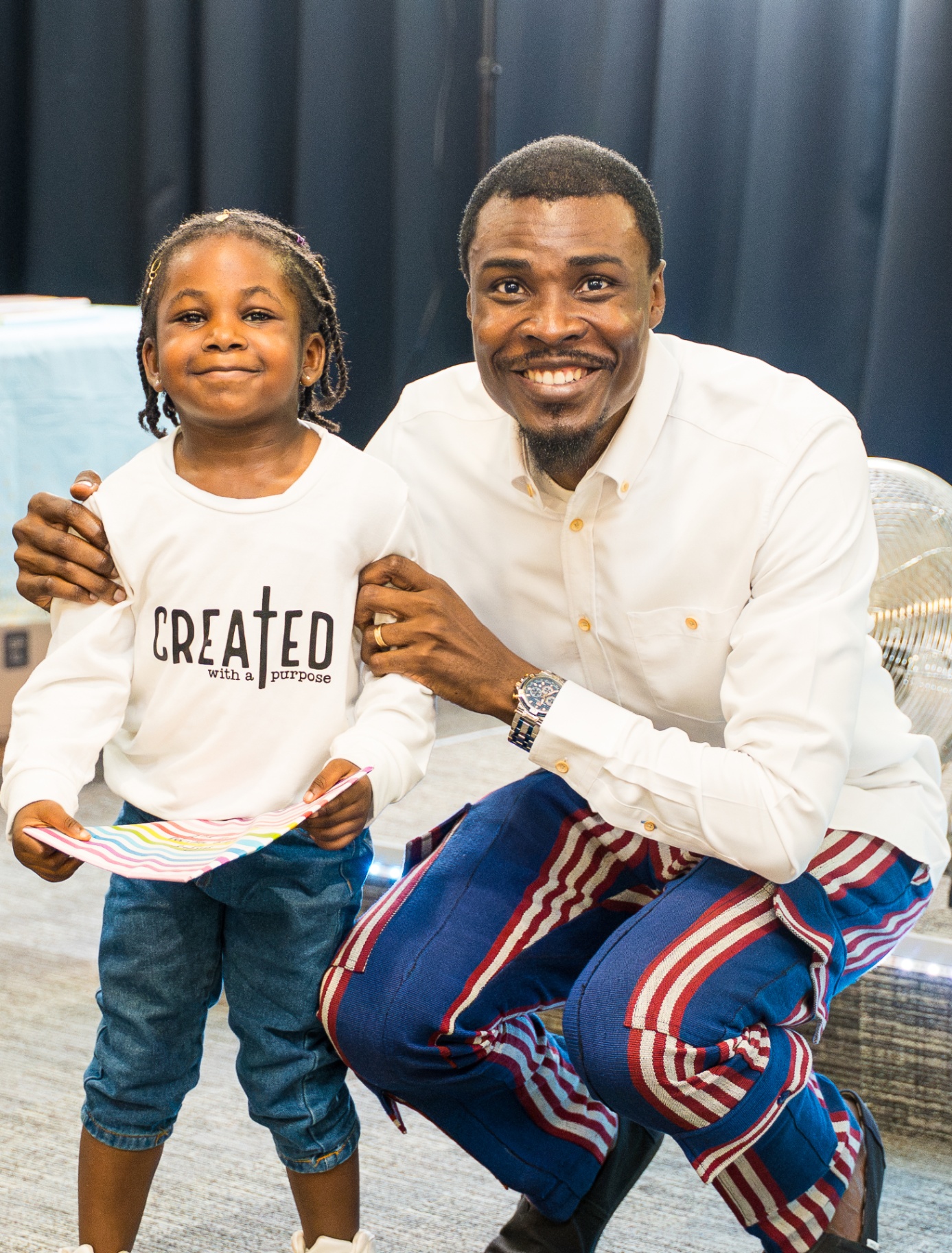 Child standing proudly beside a church leader with a gift in hand