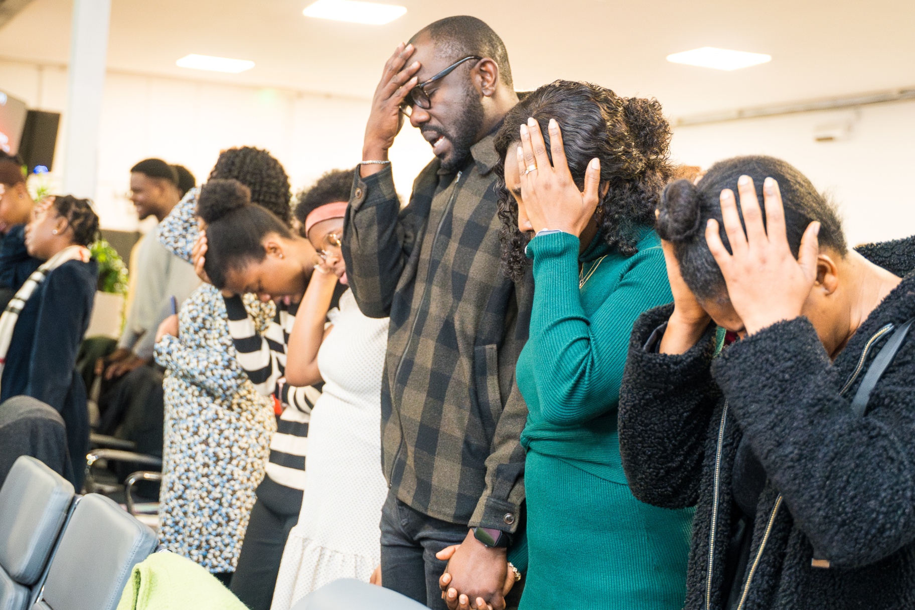 Congregation in prayer with hands on heads
