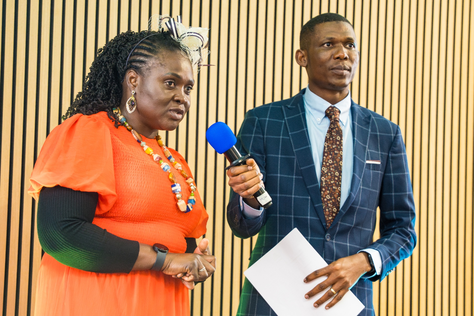 Woman in orange dress sharing testimony during service