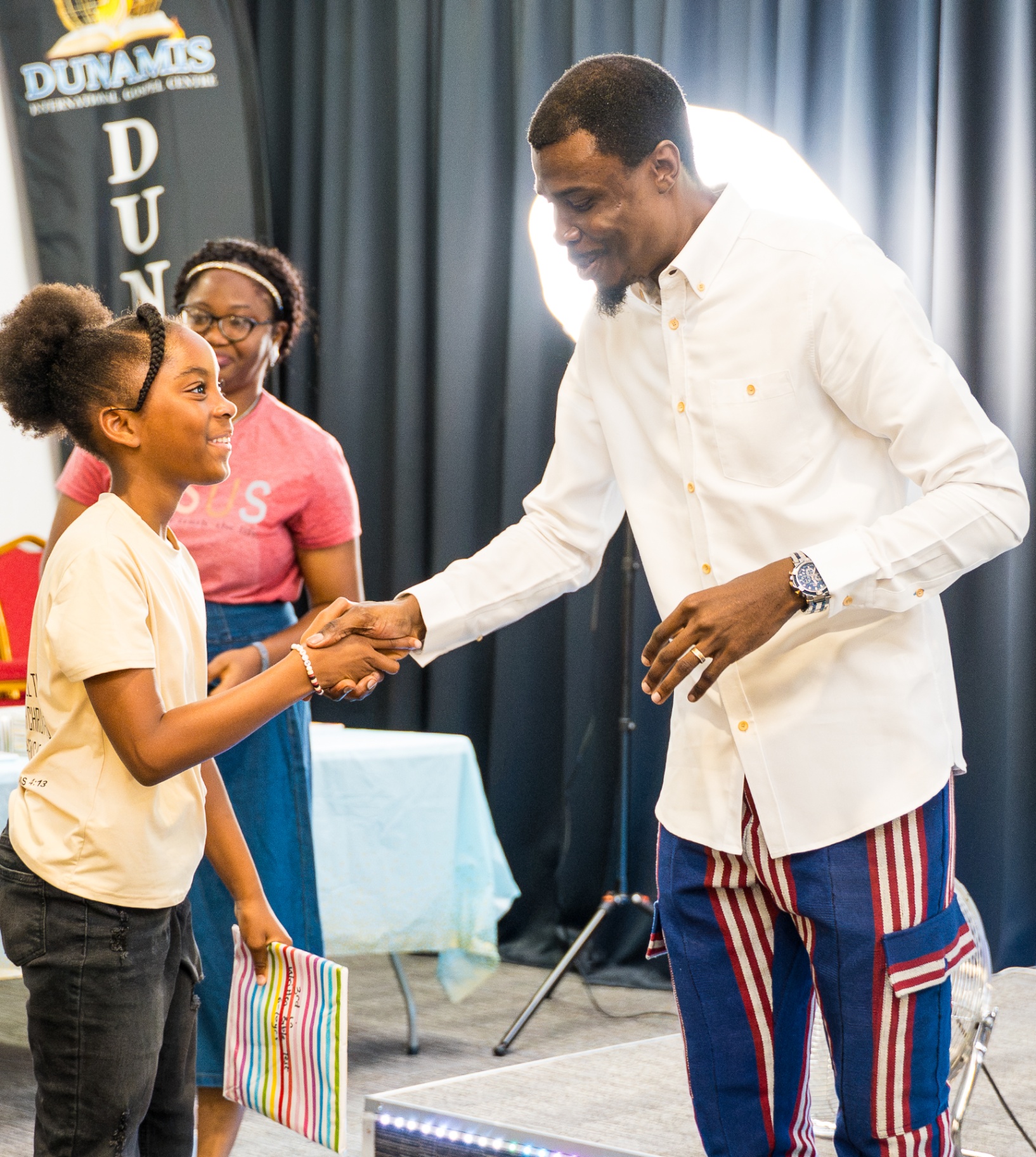 Church leader shaking hands with a child during presentation