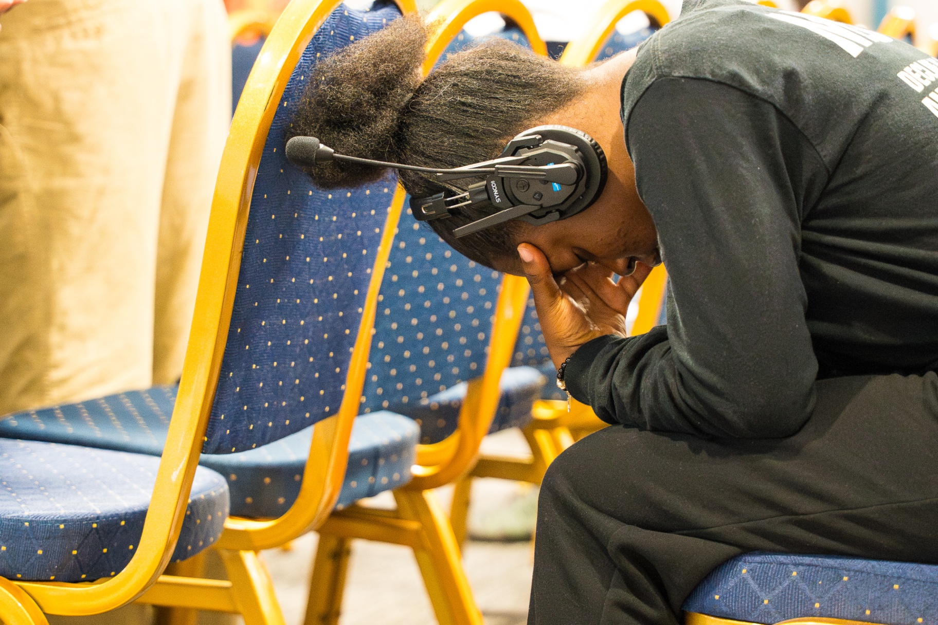 Worshipper bowed in prayer wearing a translation headset