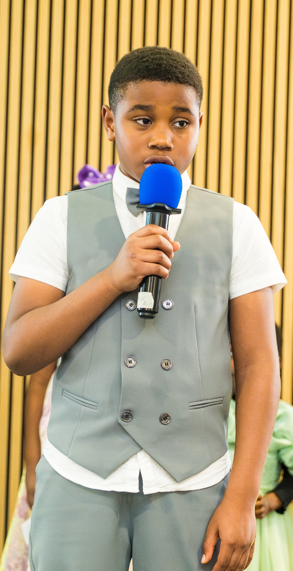 Young boy speaking into a microphone during Kids and Youth presentation