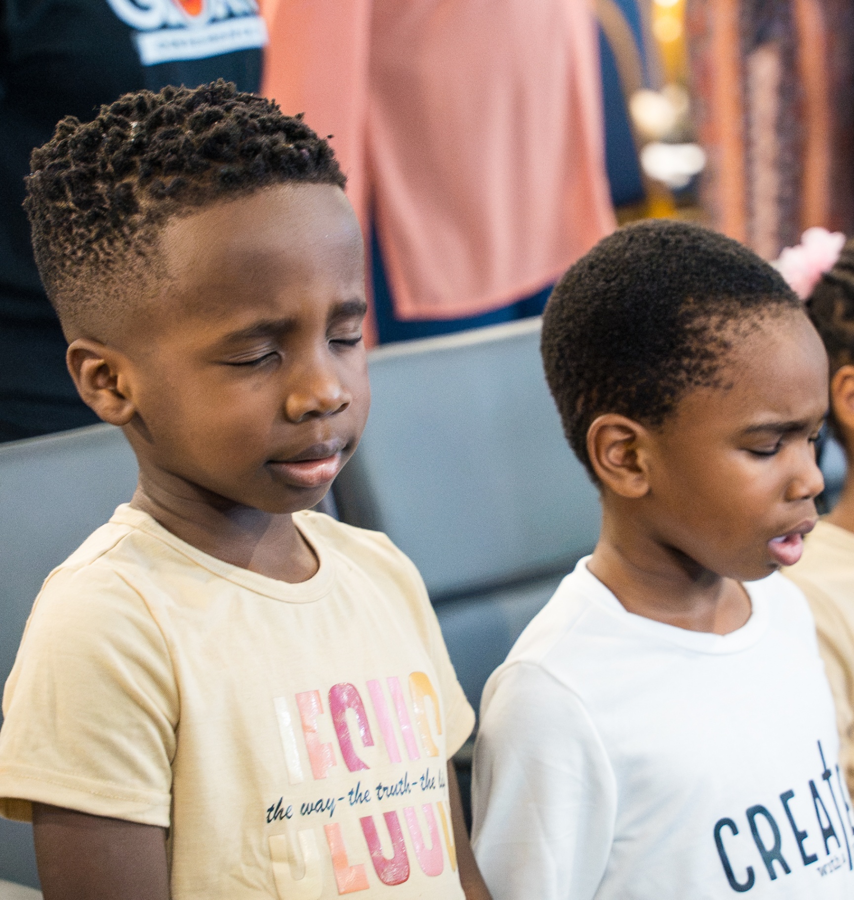 Two boys worshipping with eyes closed during service