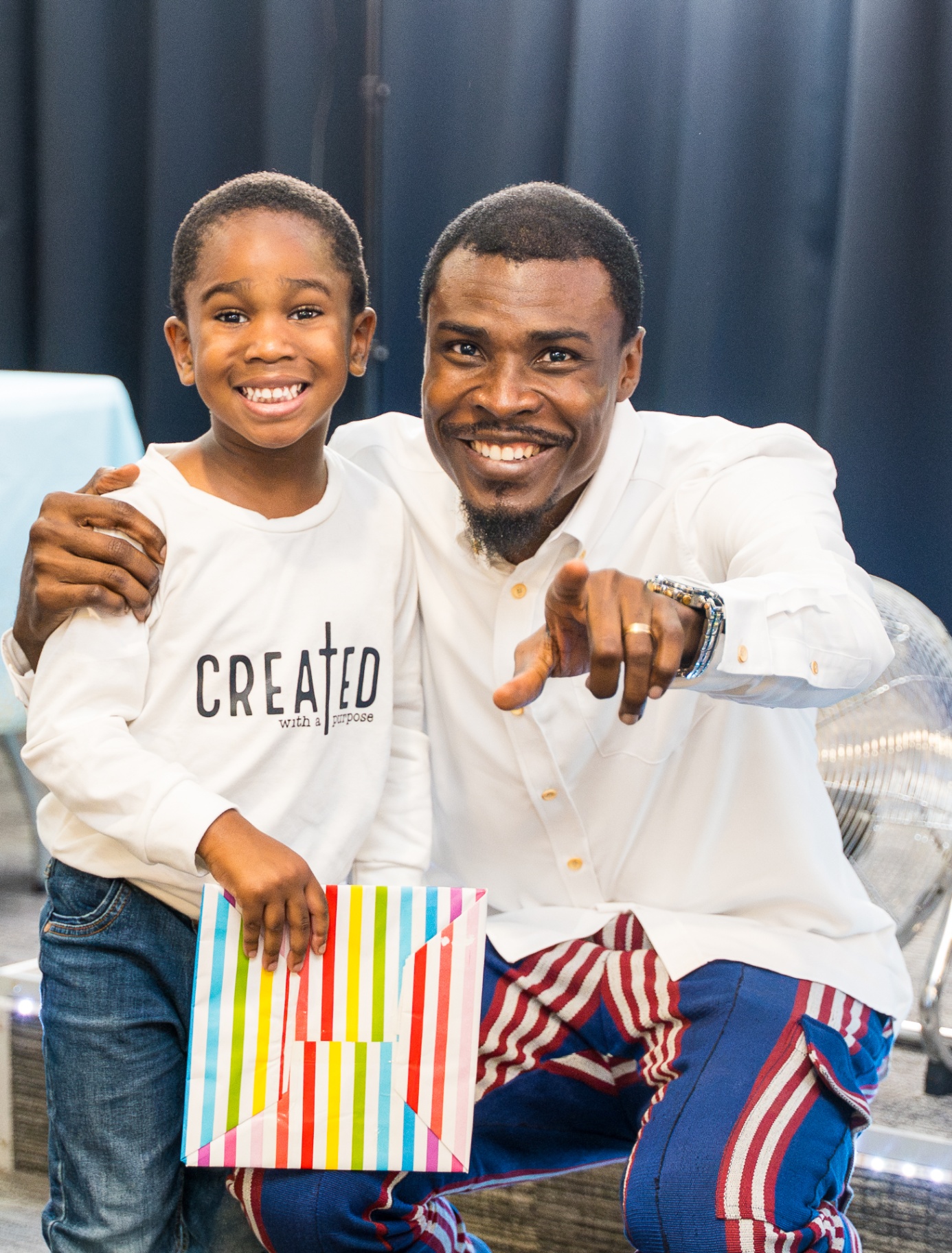 Child smiling beside a church leader while holding a gift bag