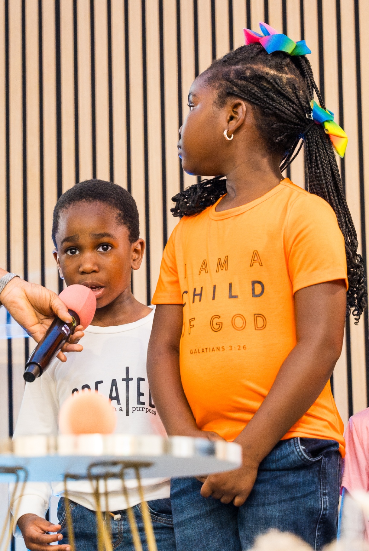 Two children sharing during Kids and Youth service, one wearing 'I Am a Child of God' shirt